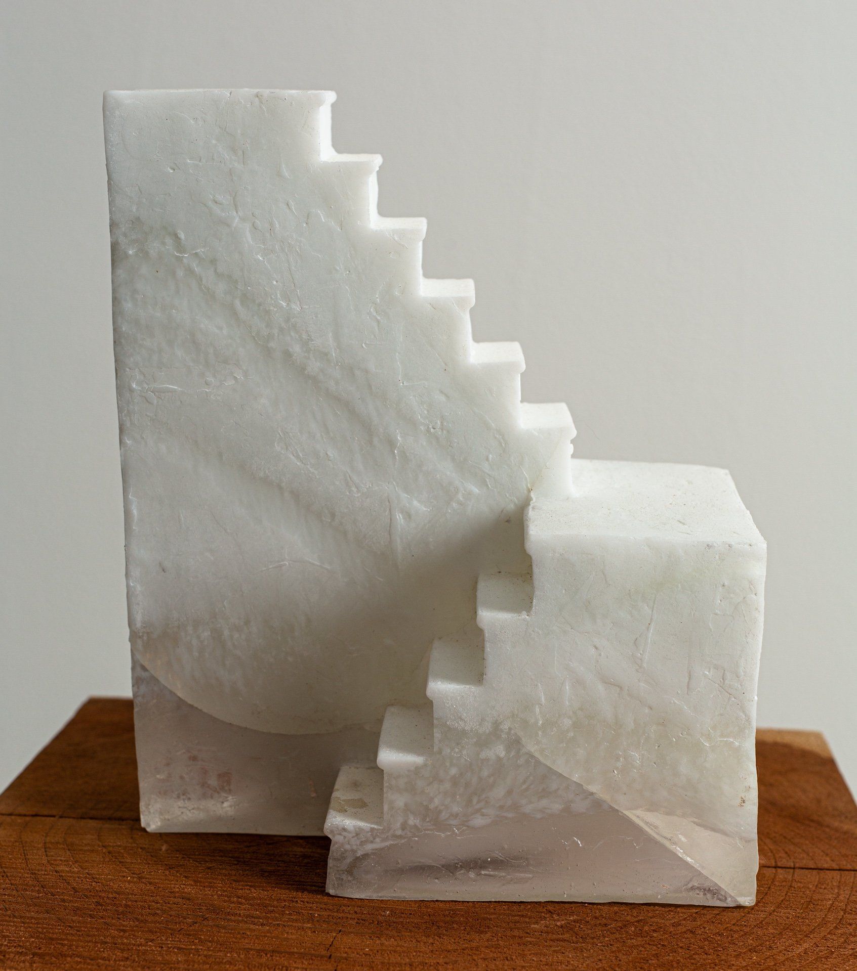 A white marble staircase sculpture is sitting on top of a wooden table.