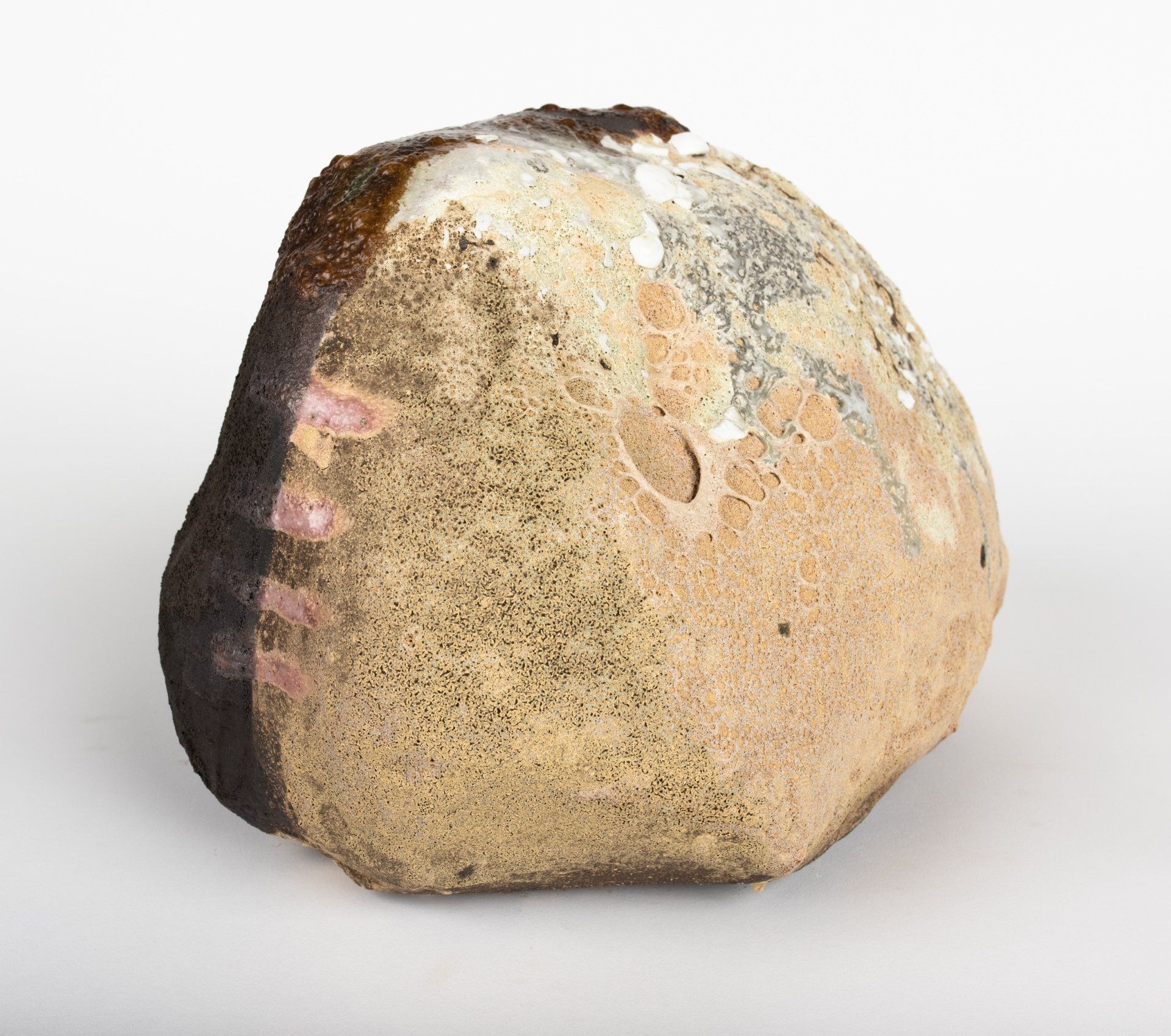 A large rock with a brown crust is sitting on a white surface