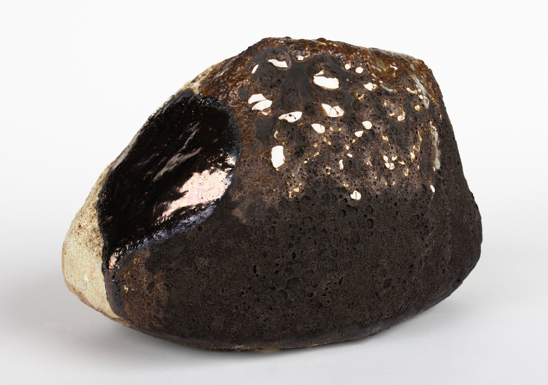 A black rock with white spots on it is on a white surface