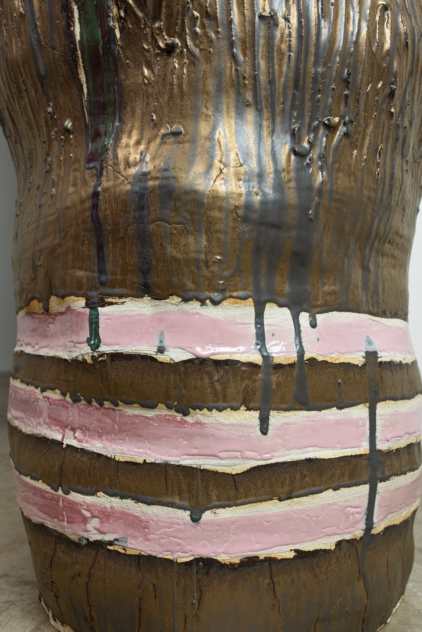 A close up of a brown and pink striped vase on a table.
