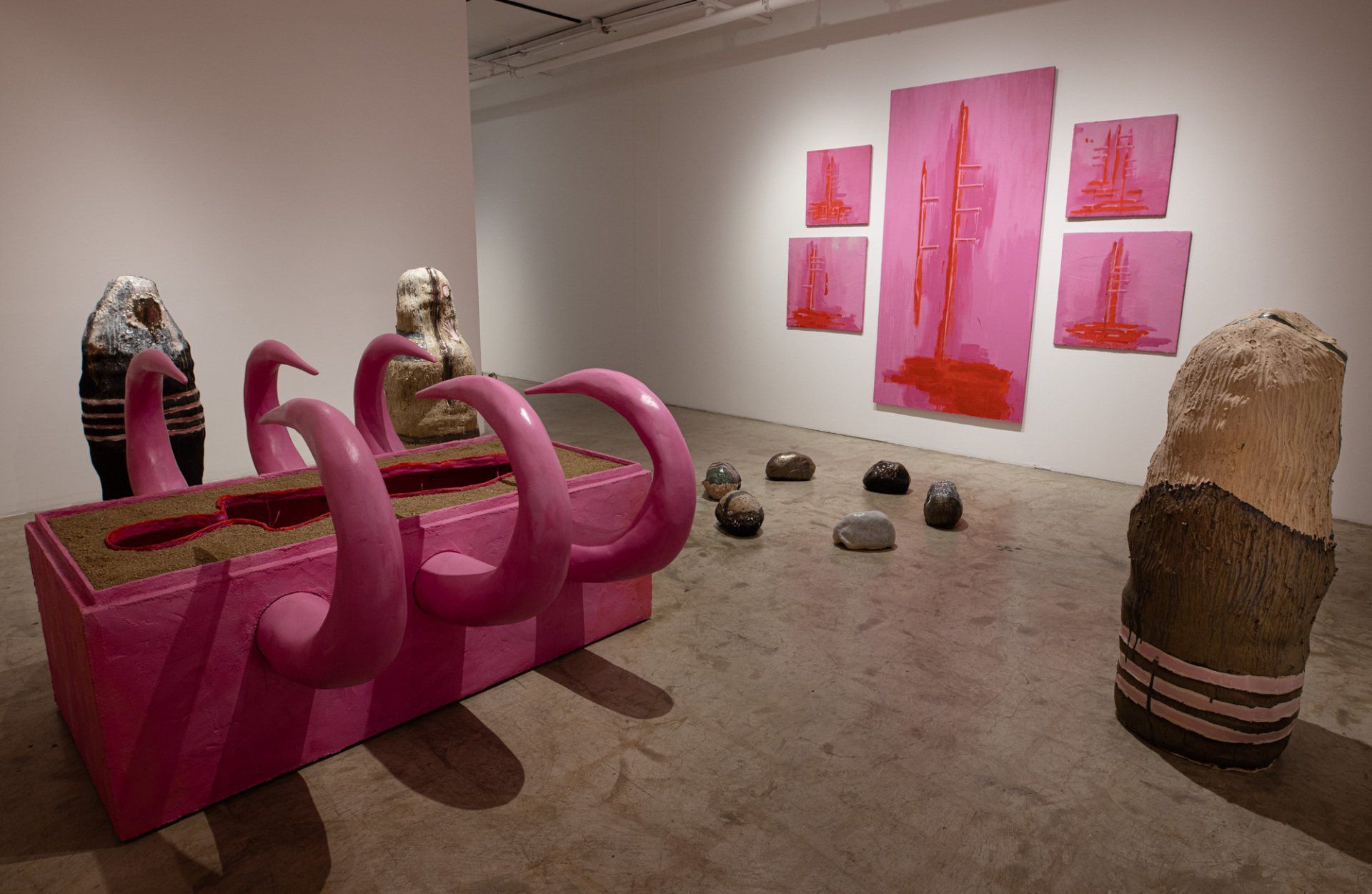A room with pink sculptures and paintings on the wall.