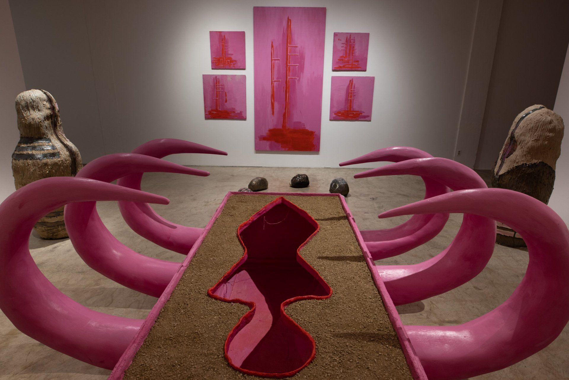 A room with pink sculptures and paintings on the wall.