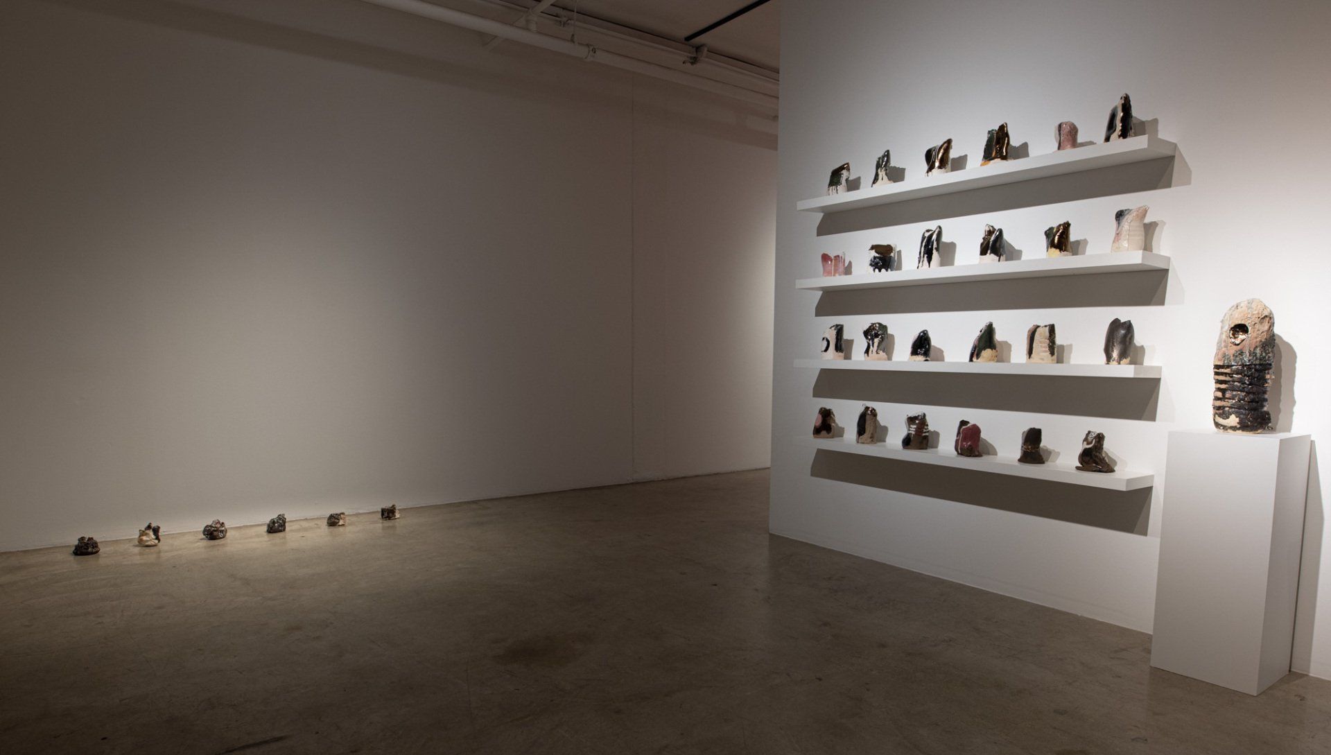 A large empty room with a row of shelves filled with sculptures.