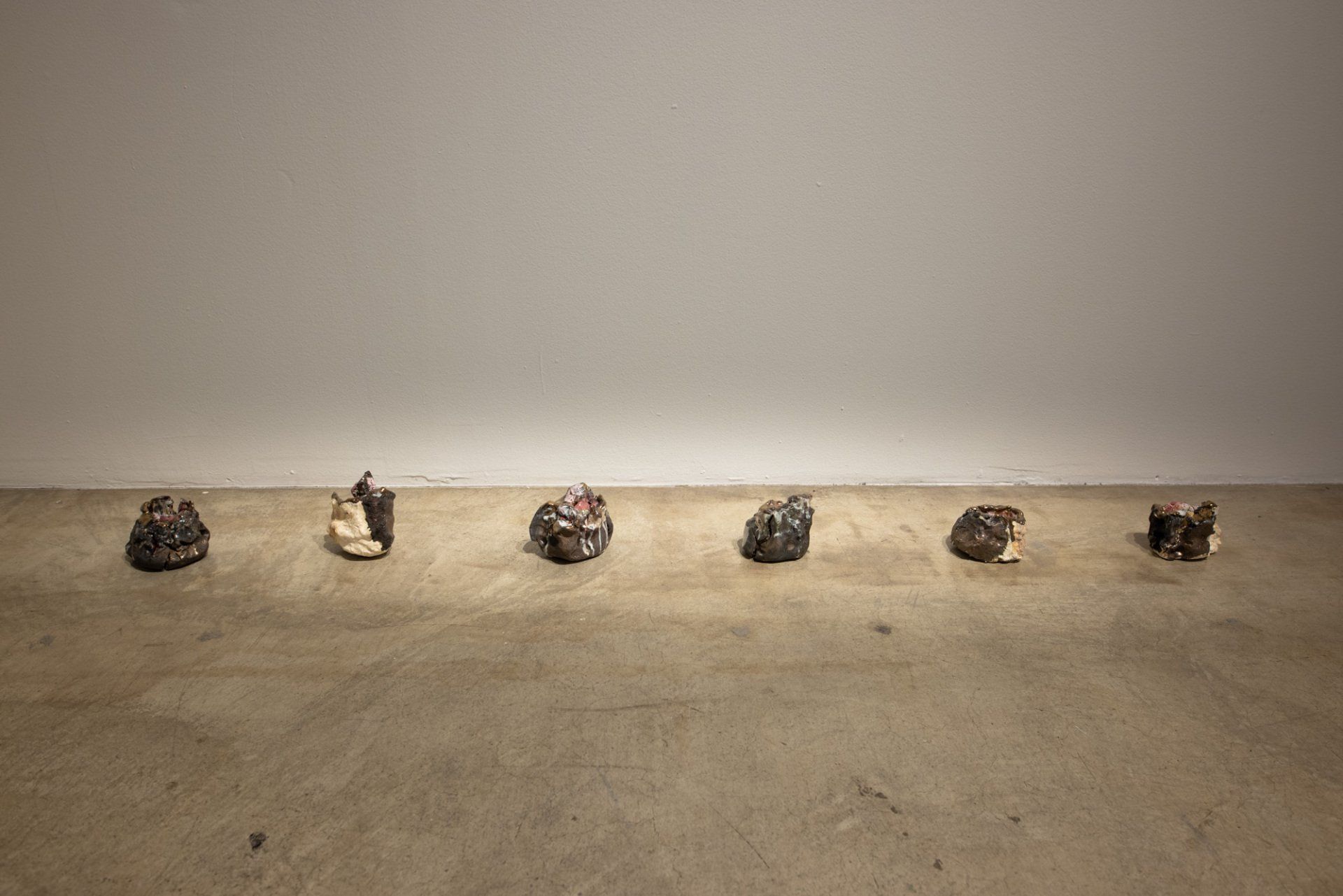 A row of sculptures are sitting on a concrete floor in a room.