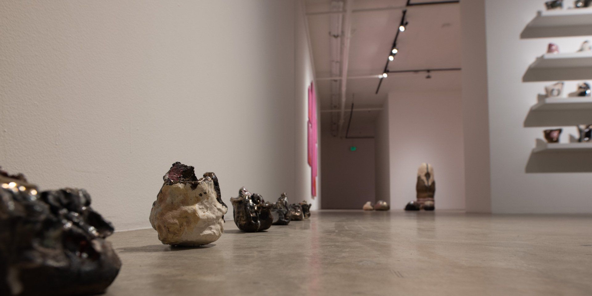 A row of sculptures are lined up on the floor of a museum.