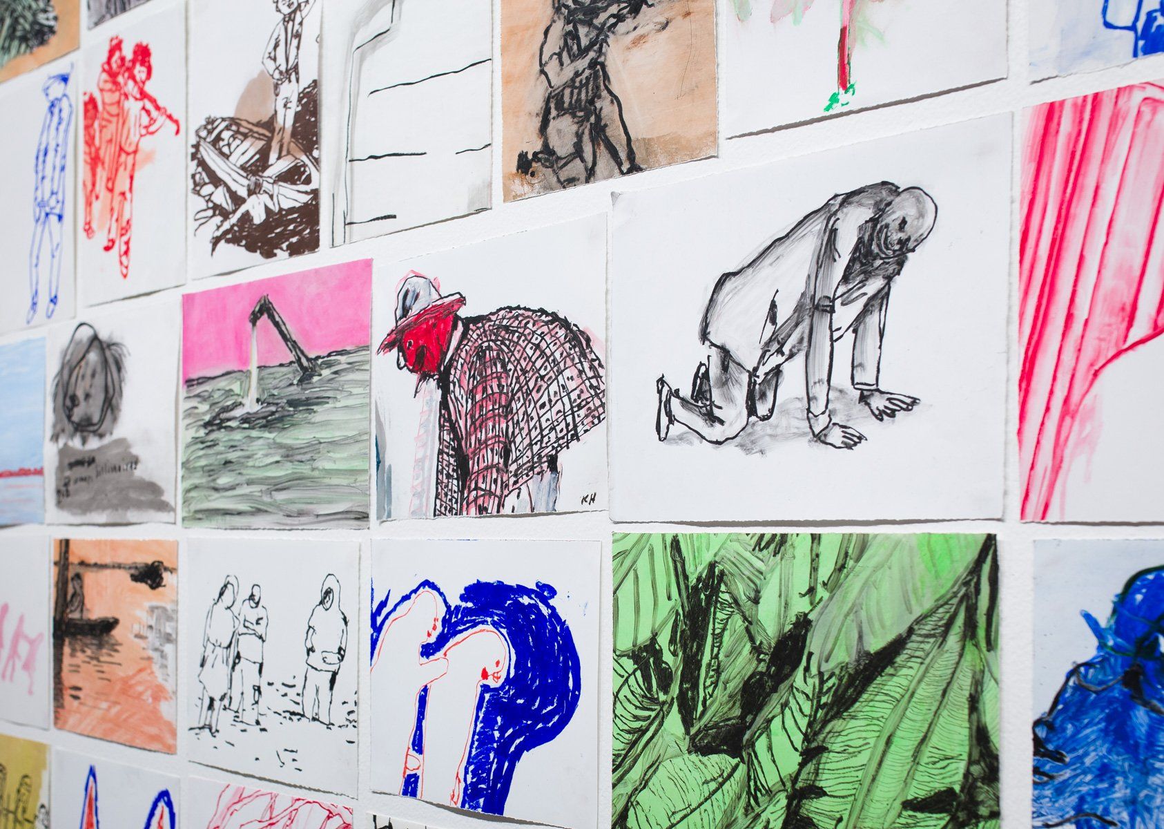 A bunch of drawings are hanging on a wall.