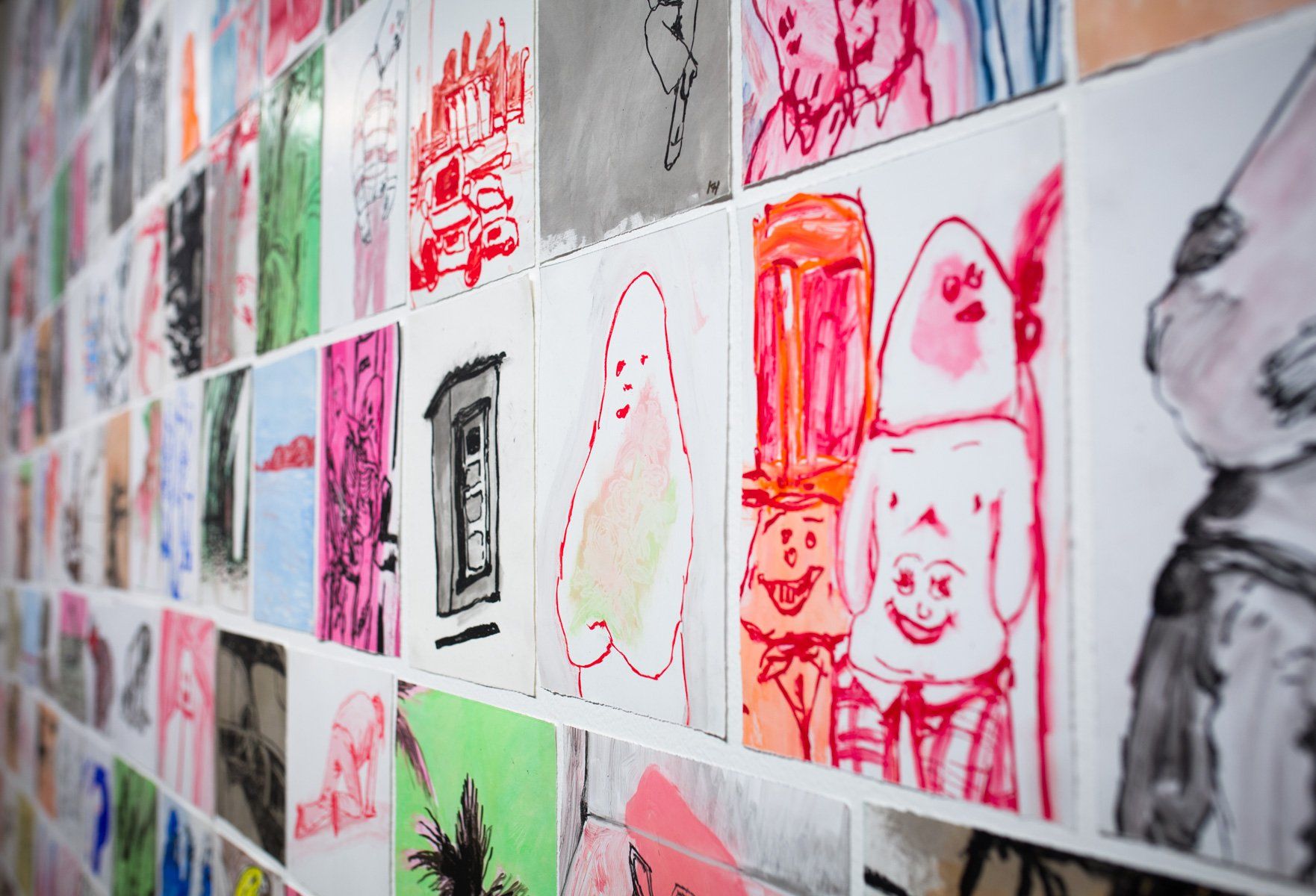 A wall filled with lots of colorful drawings on it.