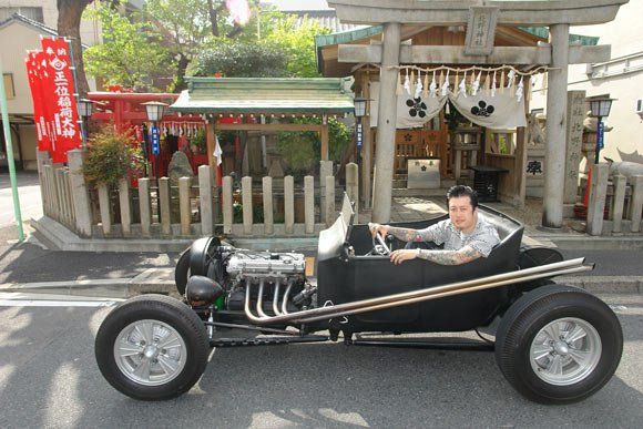 A man is driving a black car on a street.