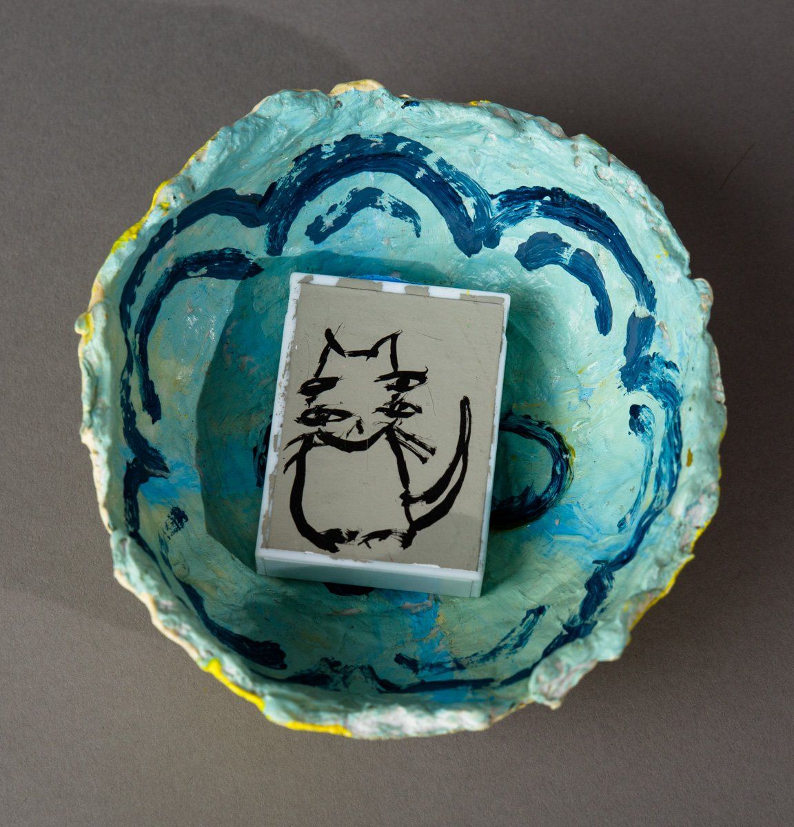 A blue bowl with a drawing of a cat on it