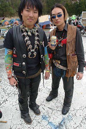 Two men are standing next to each other on a dirt road.