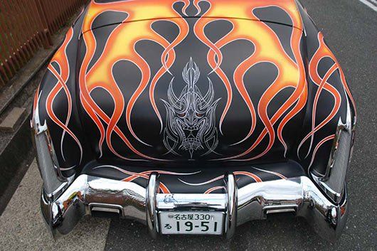 A black car with flames painted on it and a license plate that says 19-51