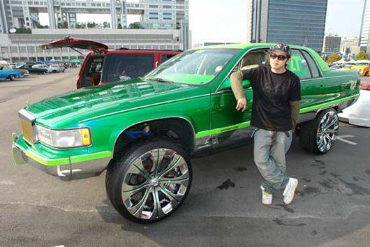 A man is standing next to a green car in a parking lot
