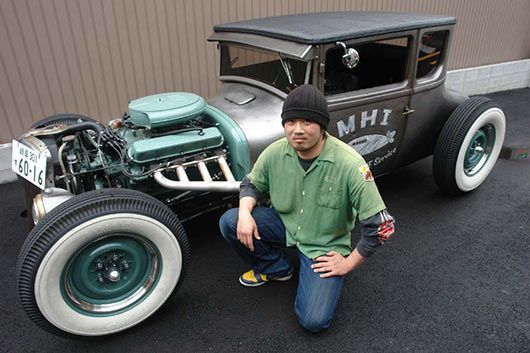 A man is kneeling in front of a car that says mhi on it