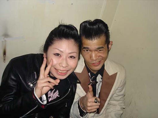 A man and a woman are posing for a picture and the woman is giving a peace sign