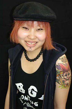 A woman with red hair is wearing a black hat and a black tank top.