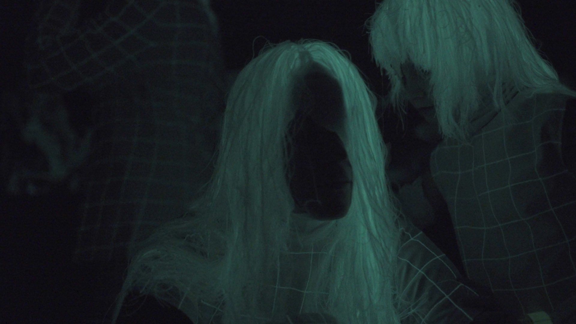 A woman with long white hair is glowing in the dark.