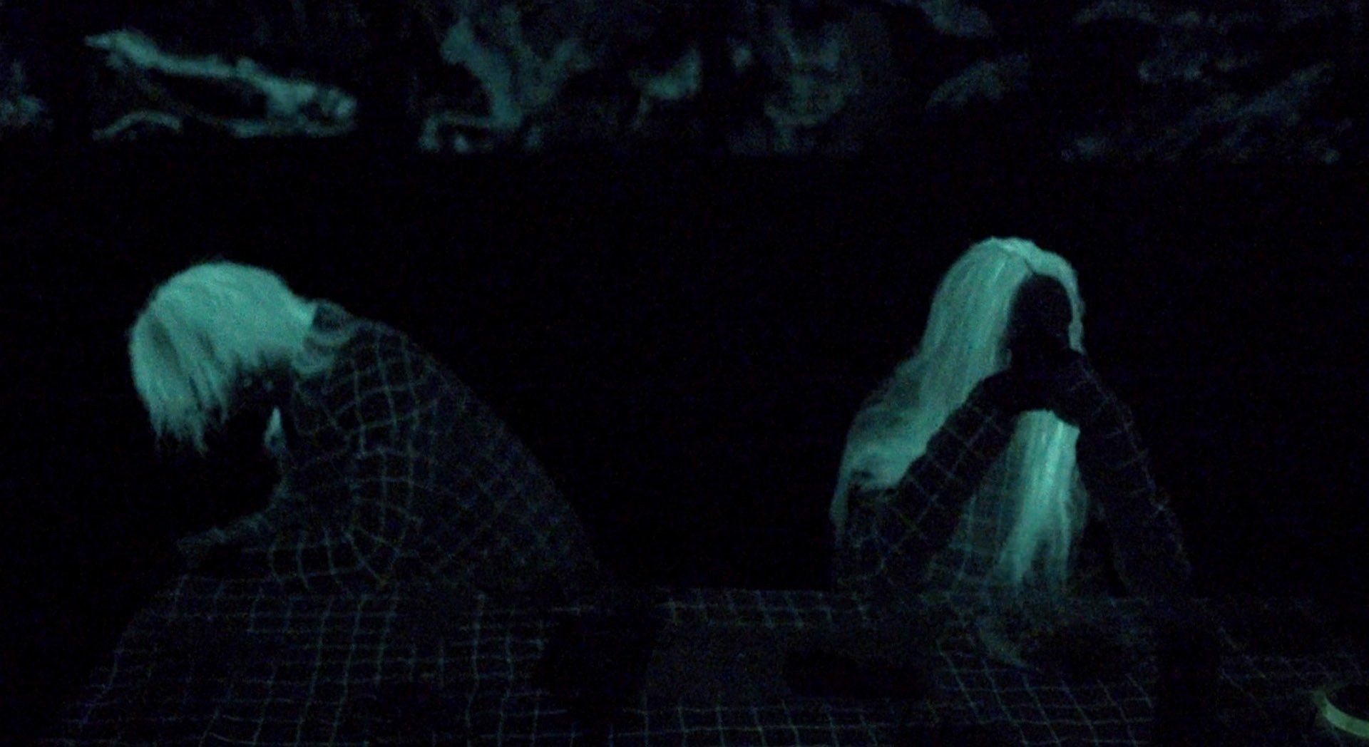 A couple of people are sitting next to each other in the dark.