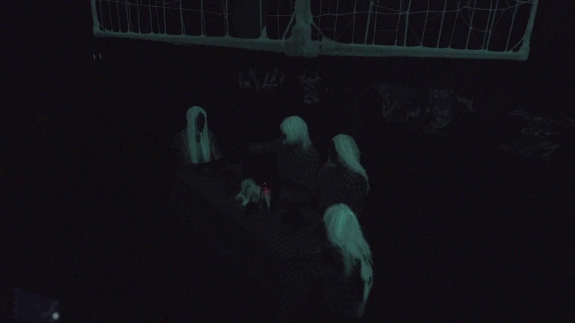 A group of ghosts are standing in the dark in front of a basketball hoop.