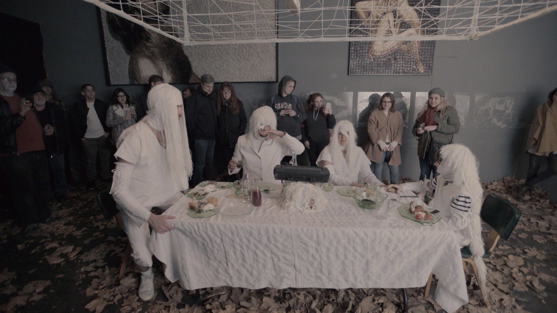 A group of people in white robes are standing around a table.