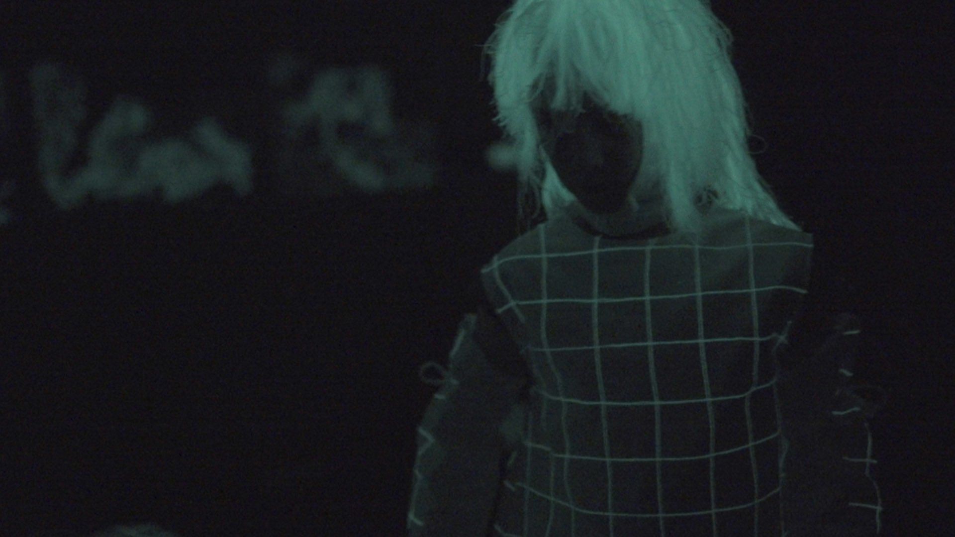 A person in a glow in the dark costume is standing in the dark.