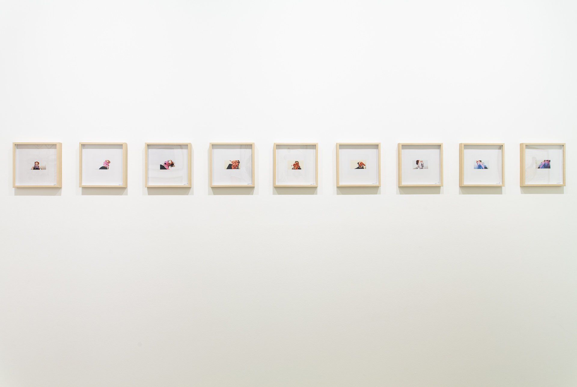 A row of framed pictures are hanging on a white wall.