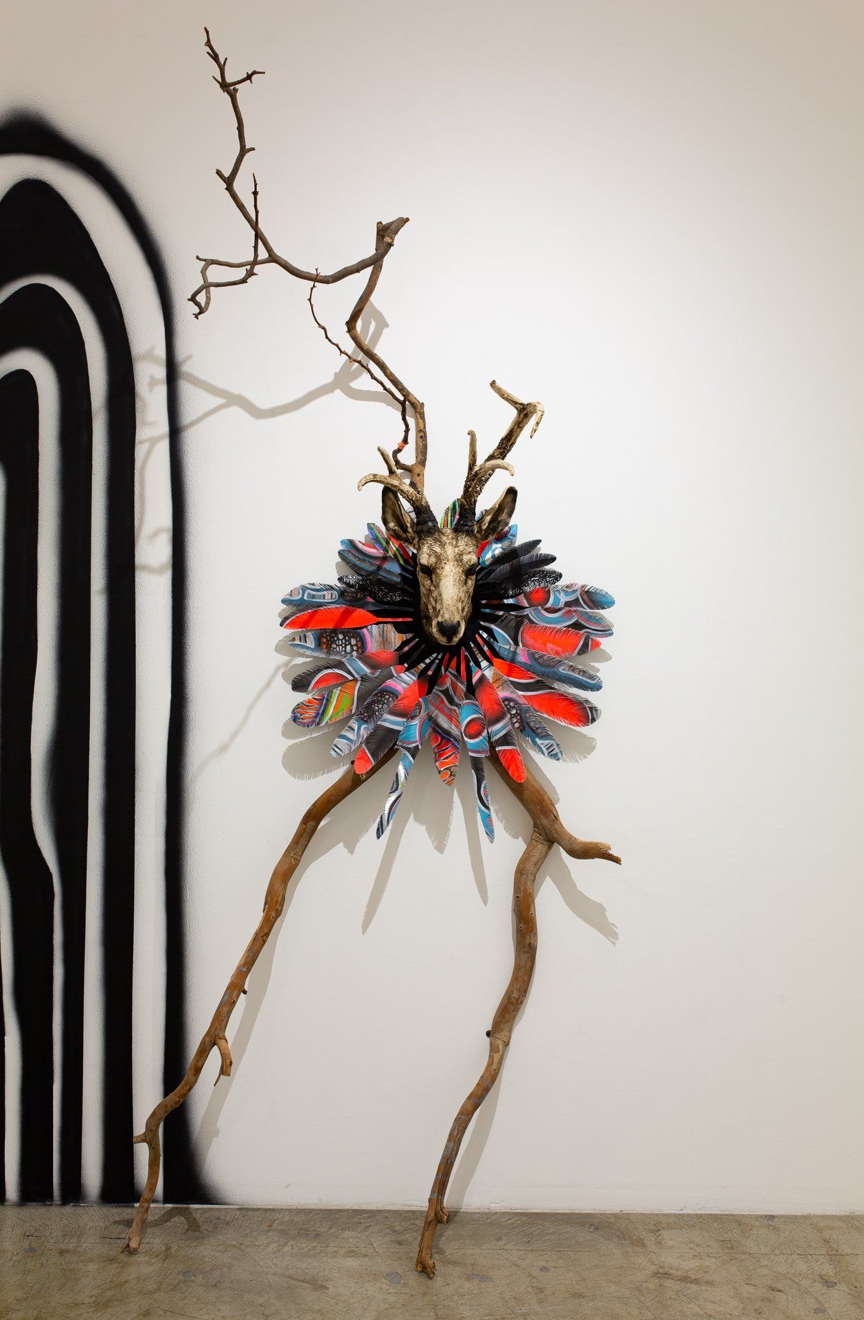 A sculpture of a deer with antlers is hanging on a wall.