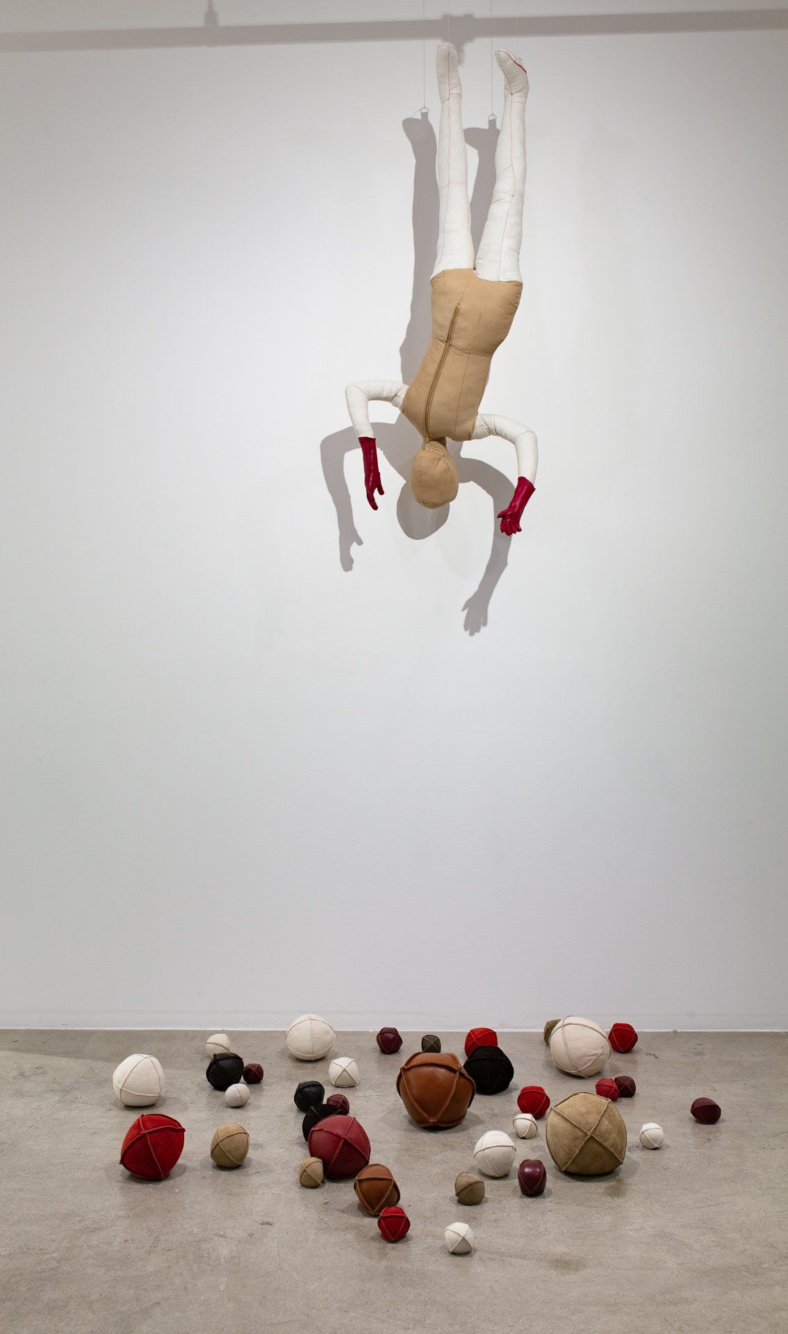 A figure hanging upside down on a white wall.