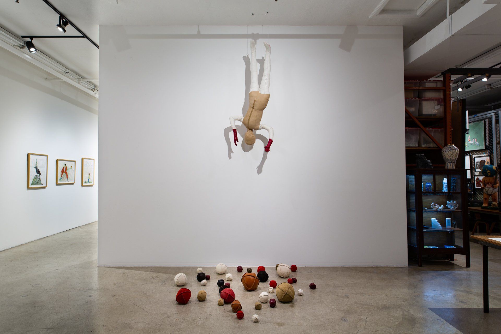 Gallery space showing dolls on the walls and on the ground.