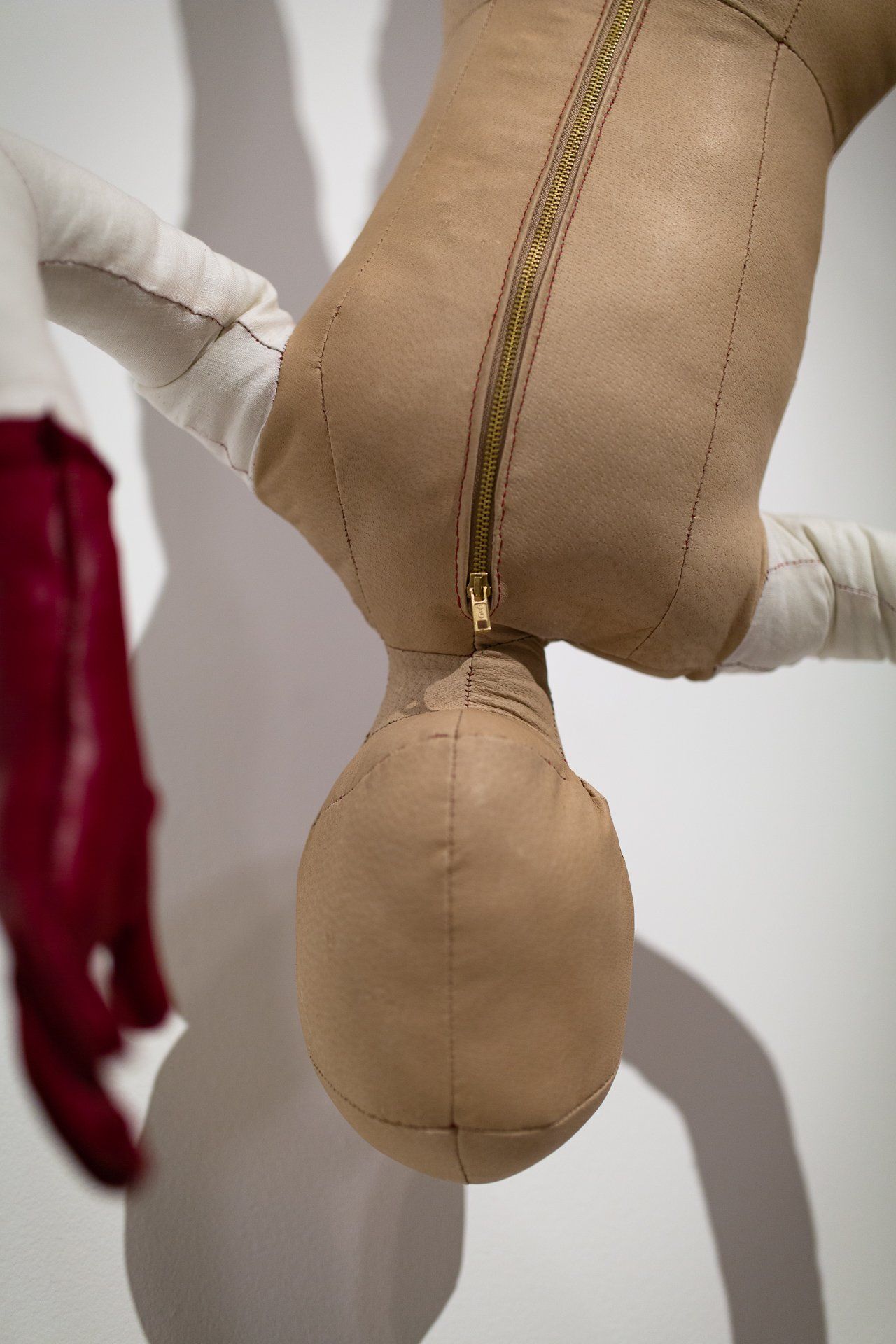 A stuffed doll is hanging upside down on a wall.