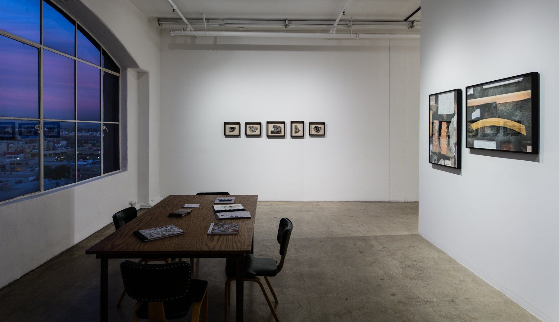A room with a table and chairs in it and paintings on the wall.