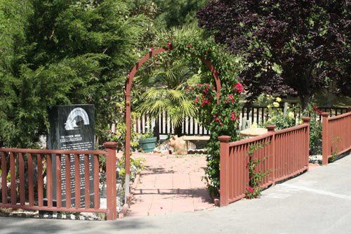 A wooden fence is surrounded by trees and flowers