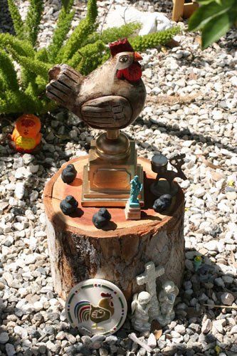 A wooden chicken statue is sitting on top of a wooden stump.