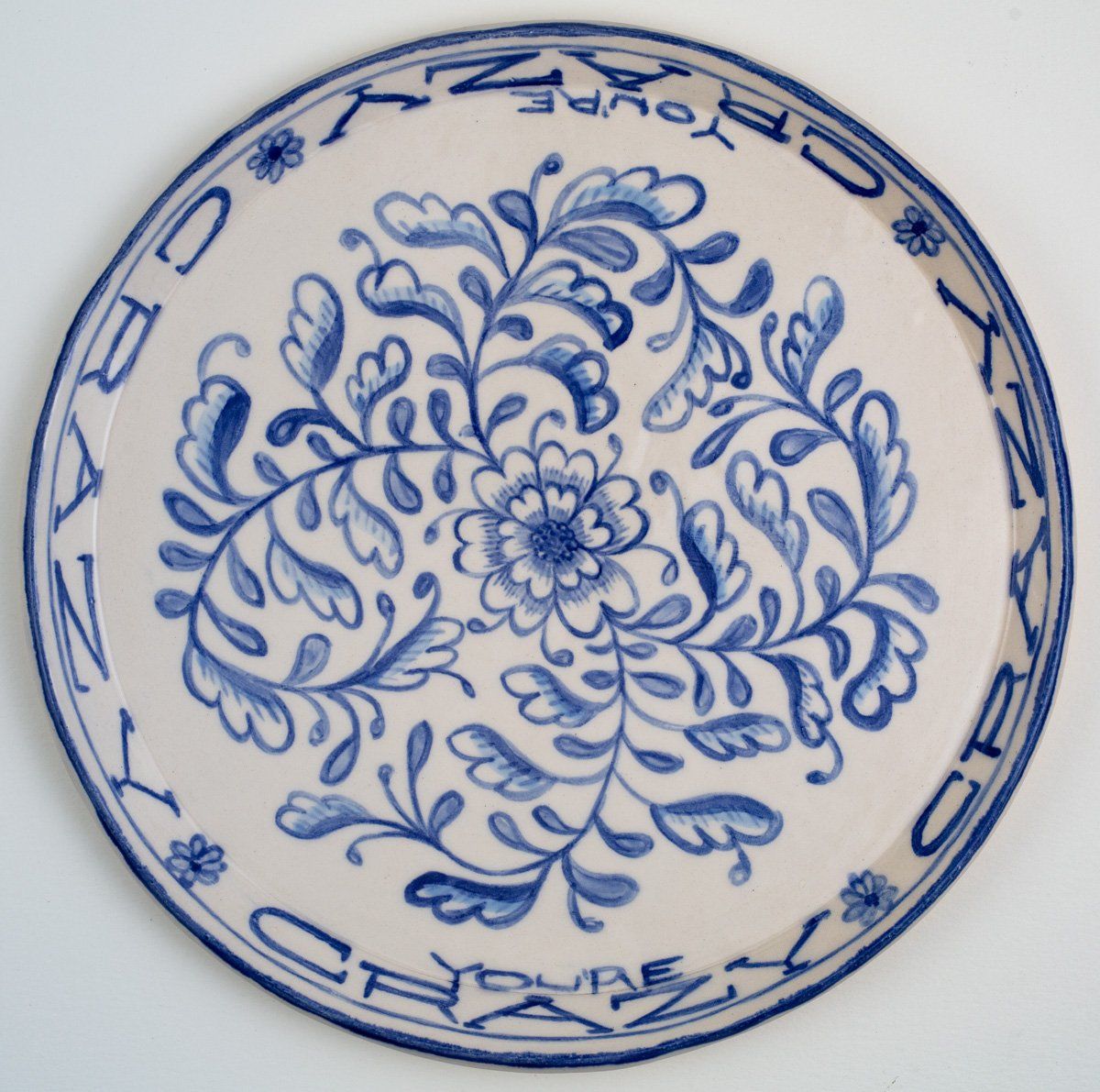 A blue and white plate that says crazy on it