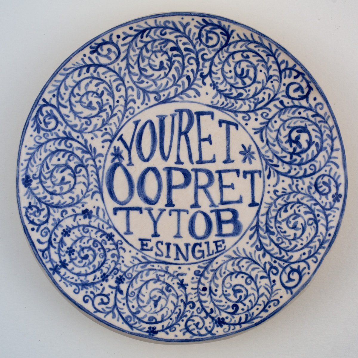 A blue and white plate that says youret oopret tytob single