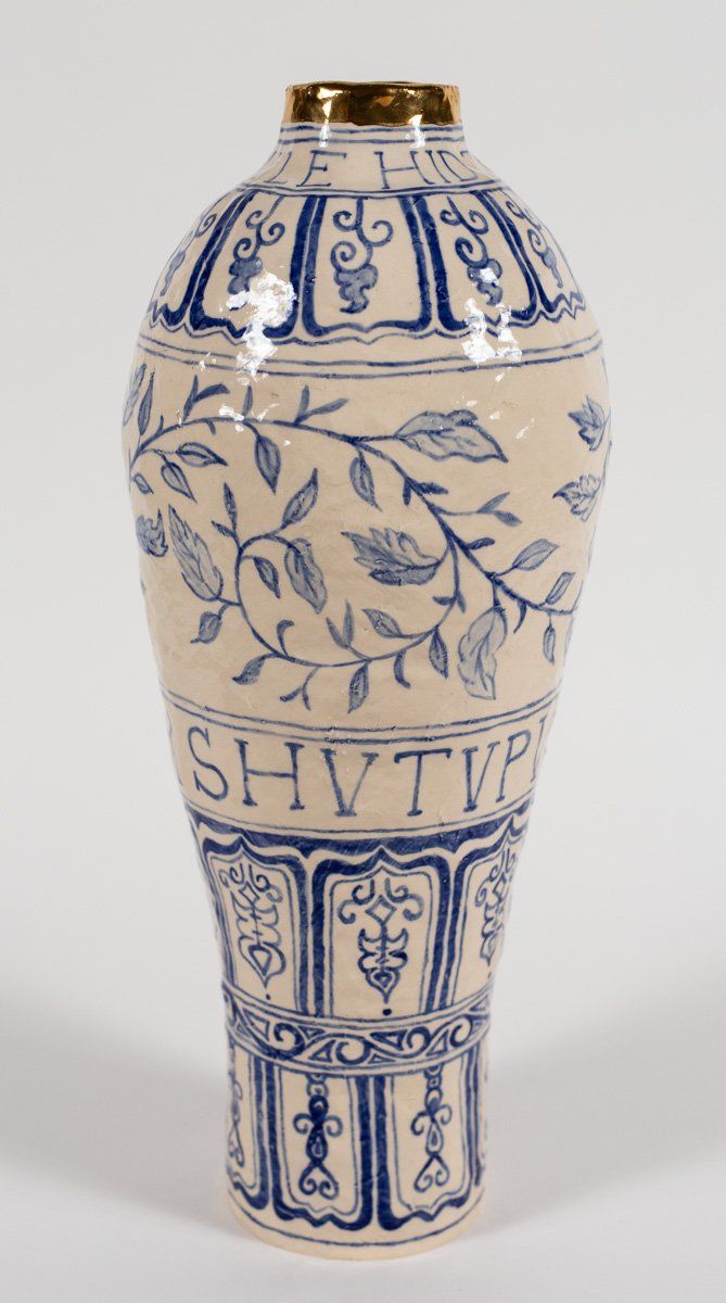 A blue and white vase with letters  on it