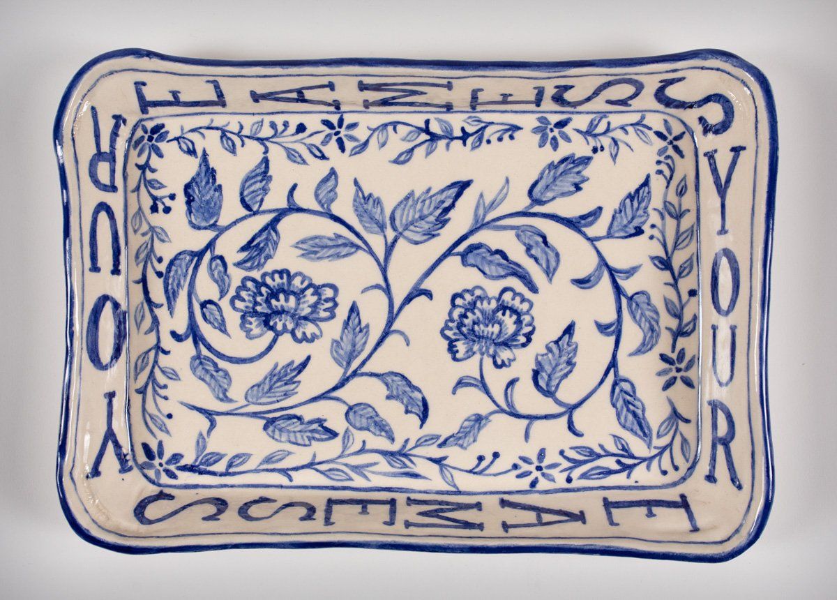 A blue and white plate with flowers and the word sesame on it