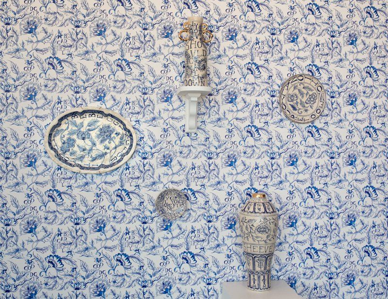 A wall with blue and white plates and vases on it