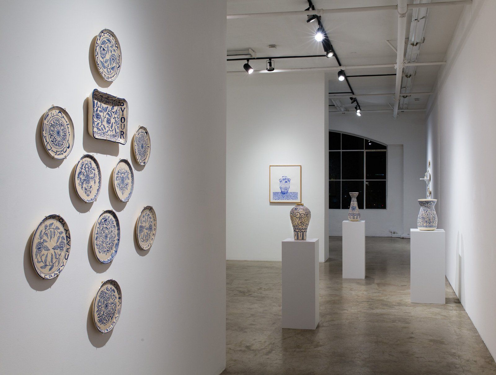A room with a lot of plates on the wall and vases on display.