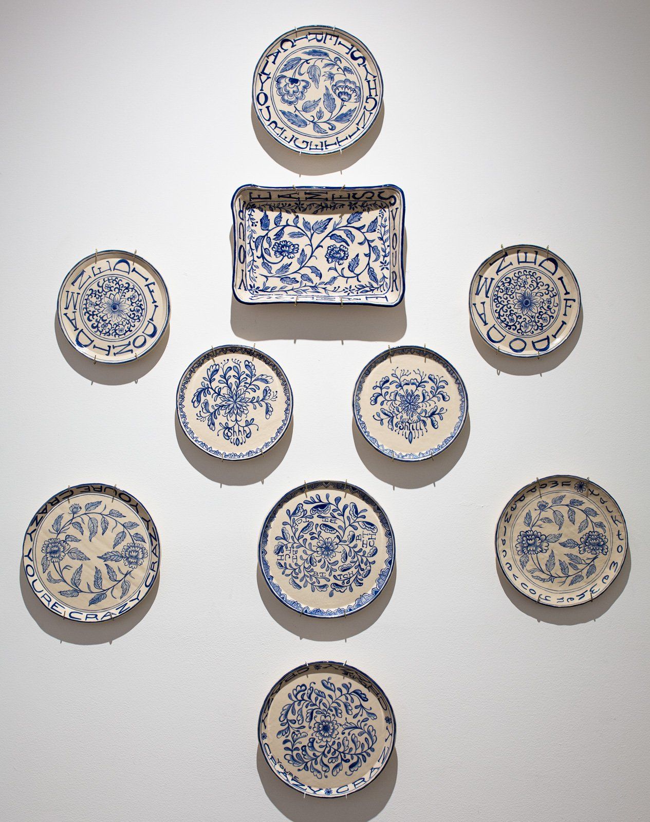 A group of blue and white plates on a white wall