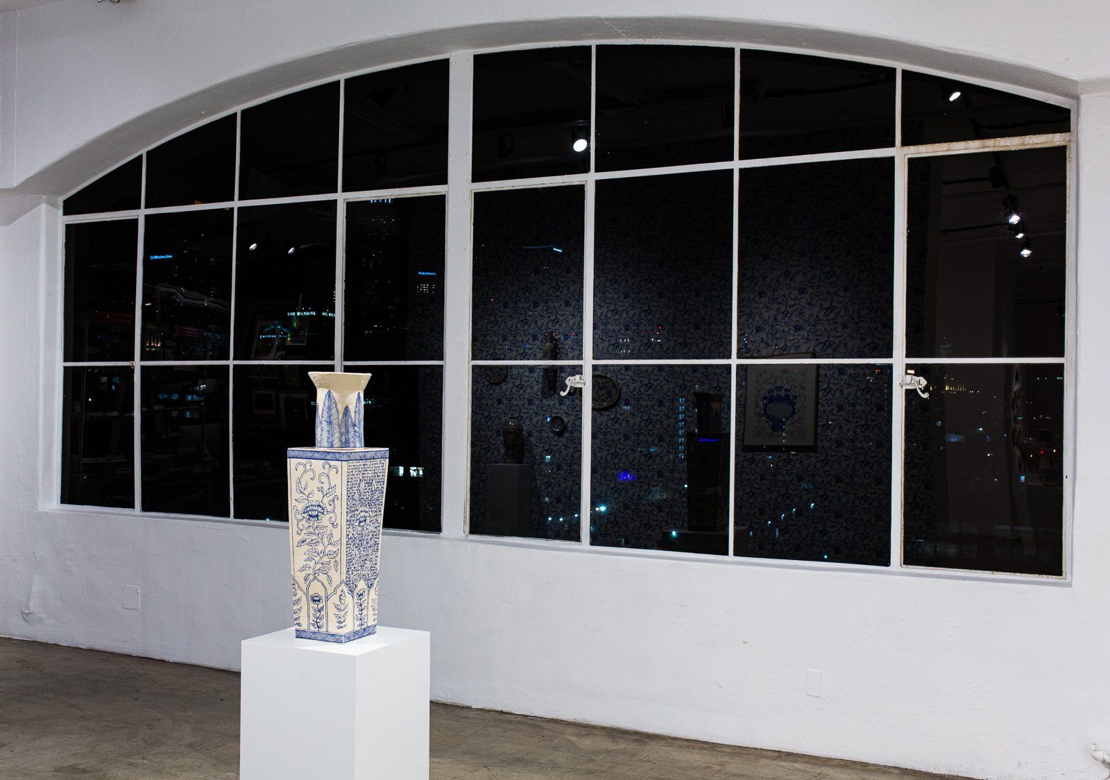 A sculpture is sitting on a pedestal in front of a large window.