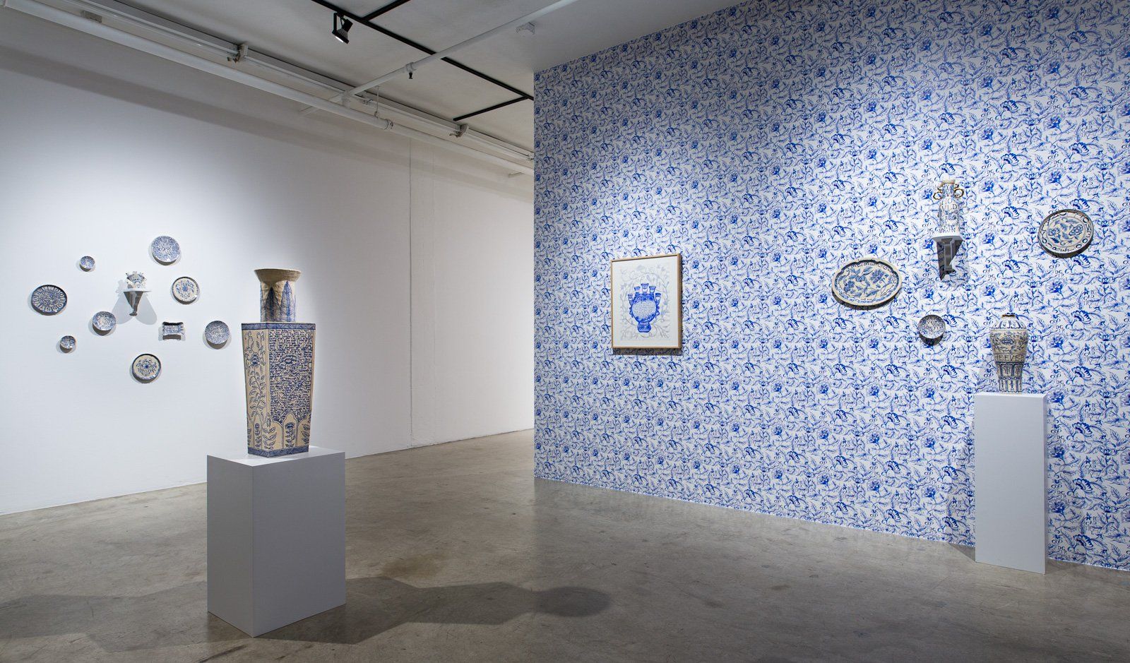 A room with a blue and white wall and vases on display.