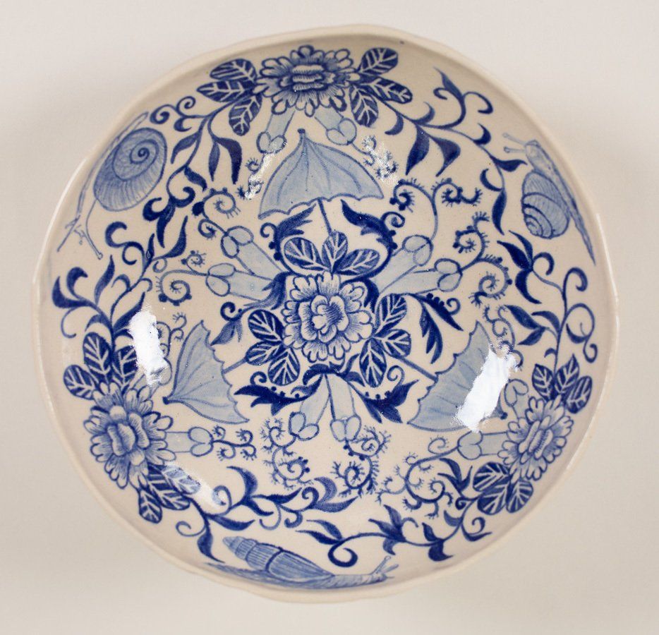 A blue and white plate with flowers and leaves on it