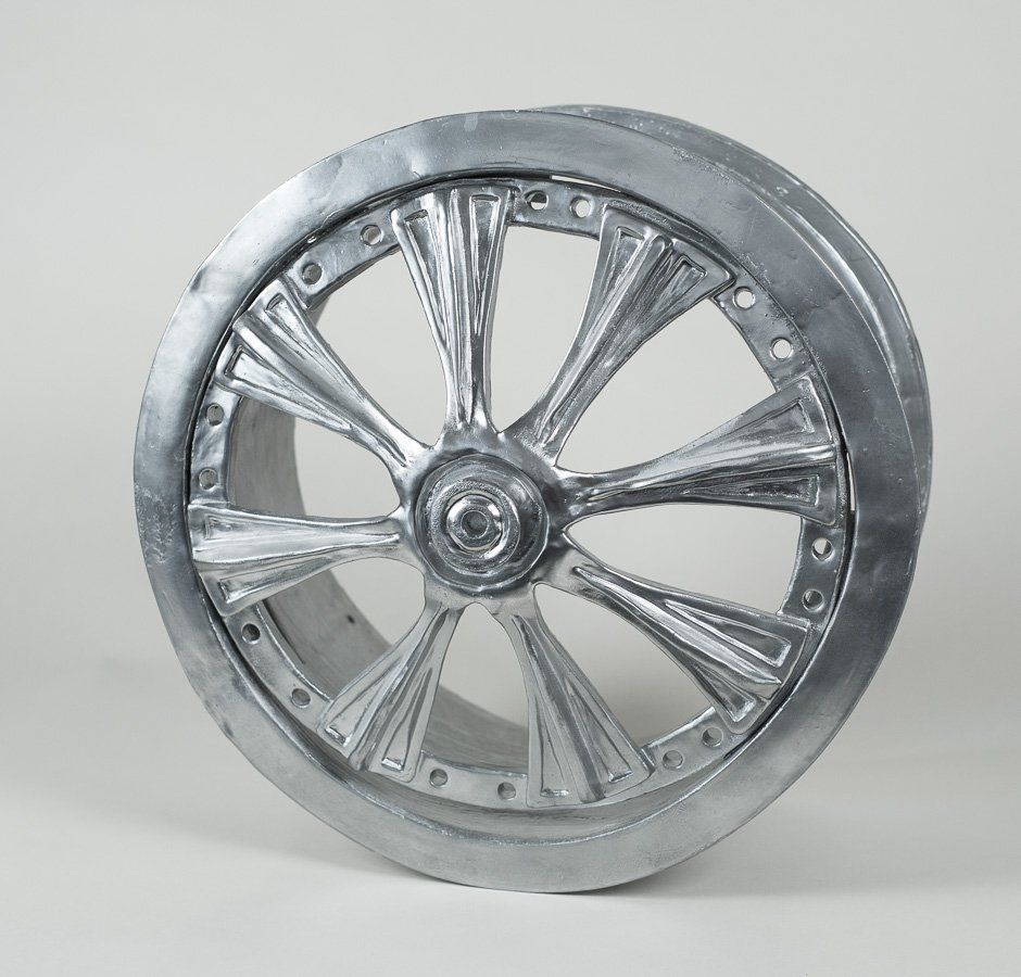 A close up of a chrome wheel on a white surface