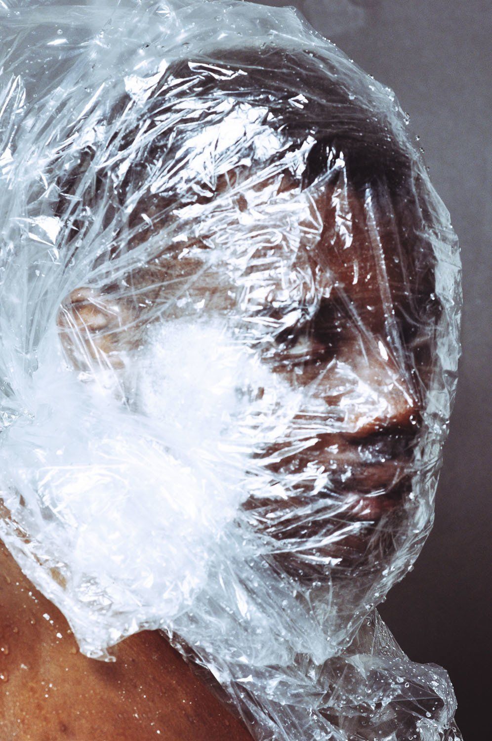 A close up of a person 's face wrapped in plastic wrap.