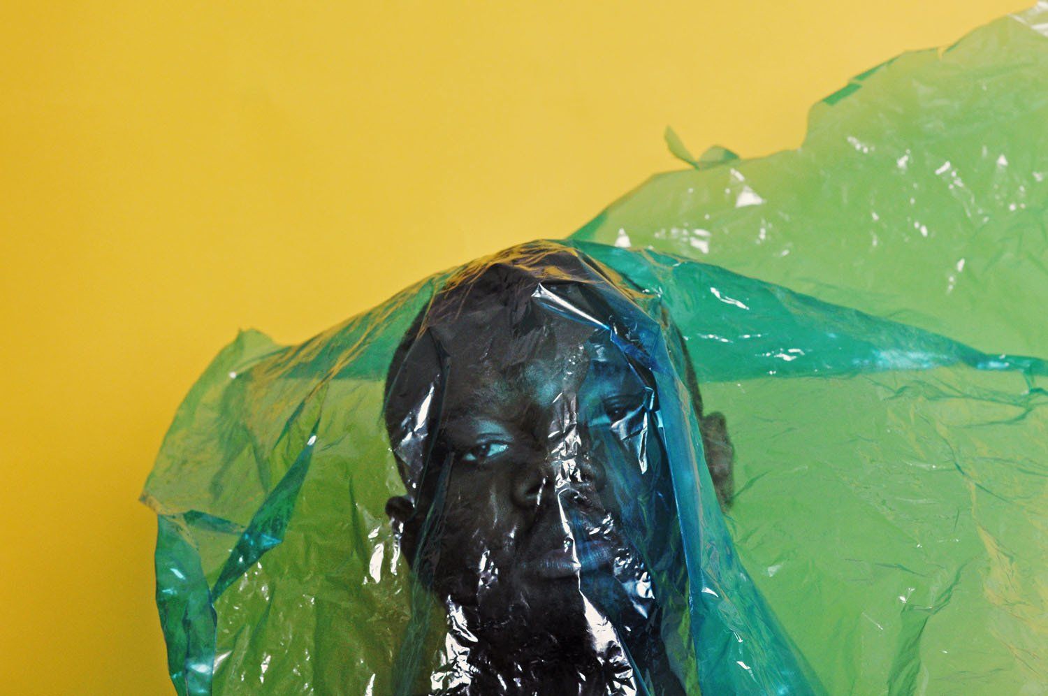 A black statue is wrapped in a green plastic bag.
