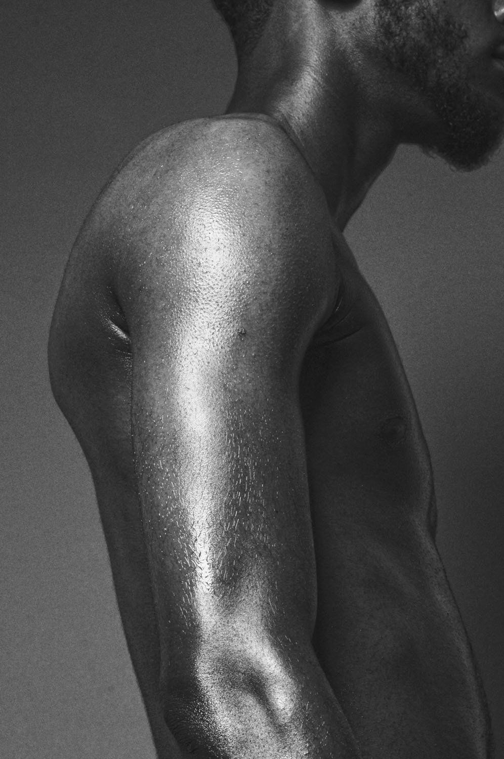 A black and white photo of a shirtless man 's arm.