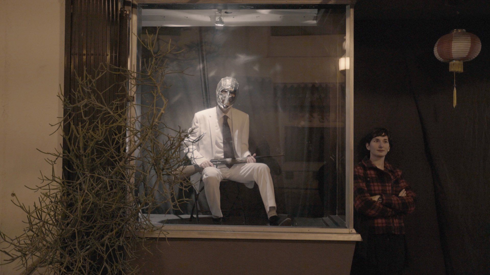 A man in a suit and tie is sitting in a glass box.
