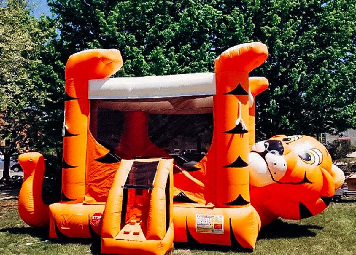 A bouncy house in the shape of a tiger is sitting in the grass.