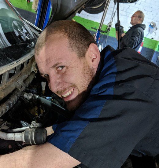 A man in a blue shirt is working on a car