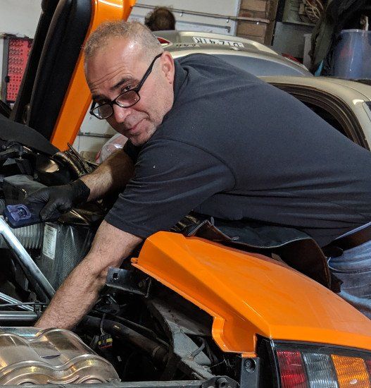 A man is working on a car with the hood open